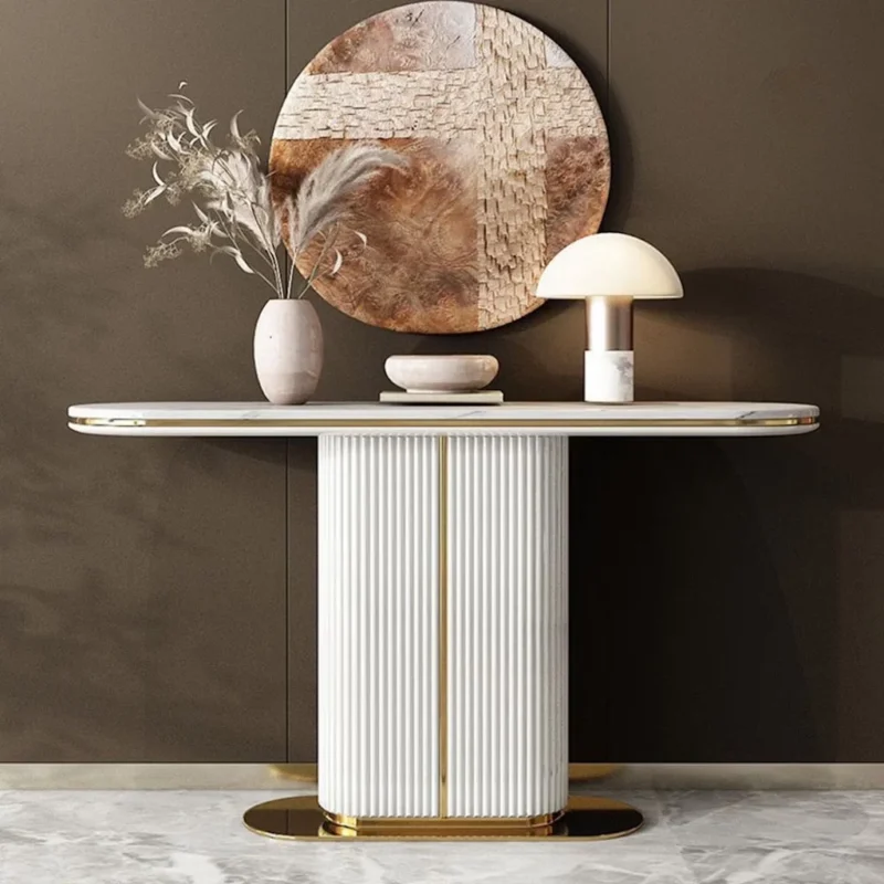 A luxurious white marble console table with a fluted pillar base and gold accents, styled with a vase of dried pampas grass, a decorative bowl, and a modern mushroom lamp against a muted wall with a large abstract round wall art piece.