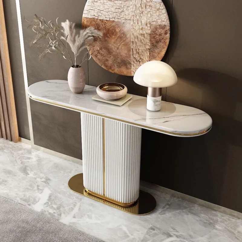 A luxurious white marble console table with a fluted pillar base and gold accents, styled with a vase of dried pampas grass, a decorative bowl, and a modern mushroom lamp against a muted wall with a large abstract round wall art piece.