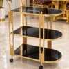 Orlena Luxe rounded edge serving trolley with gold frame and black serving surfaces