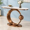 Designer marble top console table with antique copper circular frame displayed against a light blue wall.