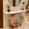 Modern black stainless steel console table with white marble top and circular base in a luxury hallway.