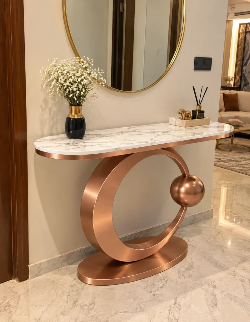 Modern black stainless steel console table with white marble top and circular base in a luxury hallway.