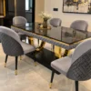 Black marble dining table with gold U shaped base and grey chairs