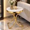 Luxury marble side table with gold curved legs beside a cream living room sofa