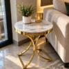 Modern gold stainless steel side table with white marble top beside sofa