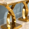 Close-up of cream marble tabletop and polished gold stainless steel curved X base