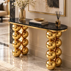 Designer black marble console table with gold stainless steel ball legs, styled with flowers, books and decorative accessories.