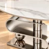 Close-up of white marble centre table top with grey veining, S-curve base and stainless steel cylindrical support.