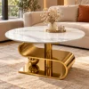 Gold marble centre table with S-curve stainless steel base placed in a luxury living room beside a cream sofa.