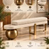 Aurevia Luxe ivory bouclé bench with spherical base, geometric stainless steel supports and textured cylindrical cushion.