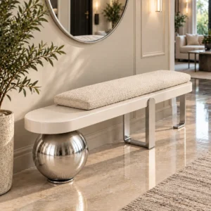 Ivory bouclé entryway bench with chrome spherical pedestal and modern metal legs beneath a round wall mirror.