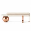 Aurevia Luxe luxury bouclé bench with ivory cylindrical cushion, cream platform, rose gold sphere and geometric stainless steel legs on white background.