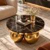 Elevated view of a round black marble coffee table with gold veining and polished gold stainless steel sphere supports.