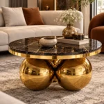 Luxury round centre table with black marble top and gold sphere base positioned in front of a beige sofa.