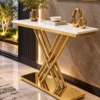 Designer gold X-base console table with rectangular white marble top and polished stainless steel rods in a modern foyer.