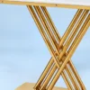 Close-up of intersecting polished gold stainless steel rods and rectangular platform base beneath a white marble console tabletop.