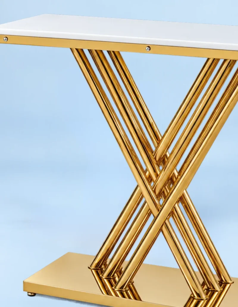 Close-up of intersecting polished gold stainless steel rods and rectangular platform base beneath a white marble console tabletop.