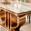 Close-up of white marble dining tabletop with grey and gold-toned veins, metallic edge trim and rose-gold stainless steel loop base.