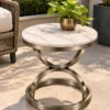 Round white marble side table with Champagne Graphite steel base displayed beside garden patio seating