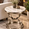 Modern marble side table with curved Champagne Graphite metal frame beside a cream sofa in a luxury living room
