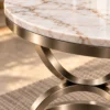 Close-up of white marble tabletop with gold veining and Champagne Graphite stainless steel curved support