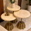 Three round cream marble side tables with fluted gold stainless steel bases