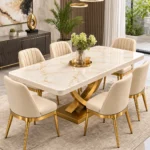 Gold stainless steel dining table with white marble top and curved X pedestal