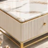 Close-up of white marble centre table showing gold and grey veining, fluted white side panels, gold knob and stainless steel frame.