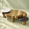 Elvessa Luxe freeform Antique brass centre table with white marble raised accent and black marble side platform against a soft green studio background.