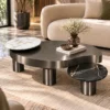 Luxury Gun Metal centre table with white and black marble accents displayed in front of a curved cream sofa in a modern living room.