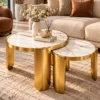 Designer marble coffee table set of two with gold stainless steel frames, styled with flowers and books in a modern lounge.