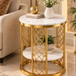 Gold marble accent table beside a beige sofa with a plant on its lower shelf