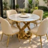 Four seater round marble dining table with cream upholstered chairs on a garden patio