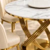 Close-up of white marble dining tabletop and gold ribbed loop base with cream chairs