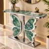 Luxury entryway console table with green marble top and silver butterfly-inspired stainless steel base beneath a round wall mirror.
