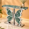 Modern butterfly console table with green marble top and polished stainless steel base in a warm luxury interior.