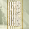 Angled gold PVD stainless steel room divider with vertical marble-look inserts