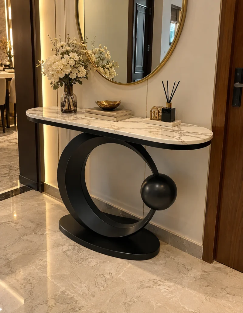 Luxury marble console table with black circular steel base styled beneath a round mirror in an entryway.