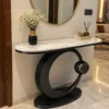 Modern black stainless steel console table with white marble top and circular base in a luxury hallway.