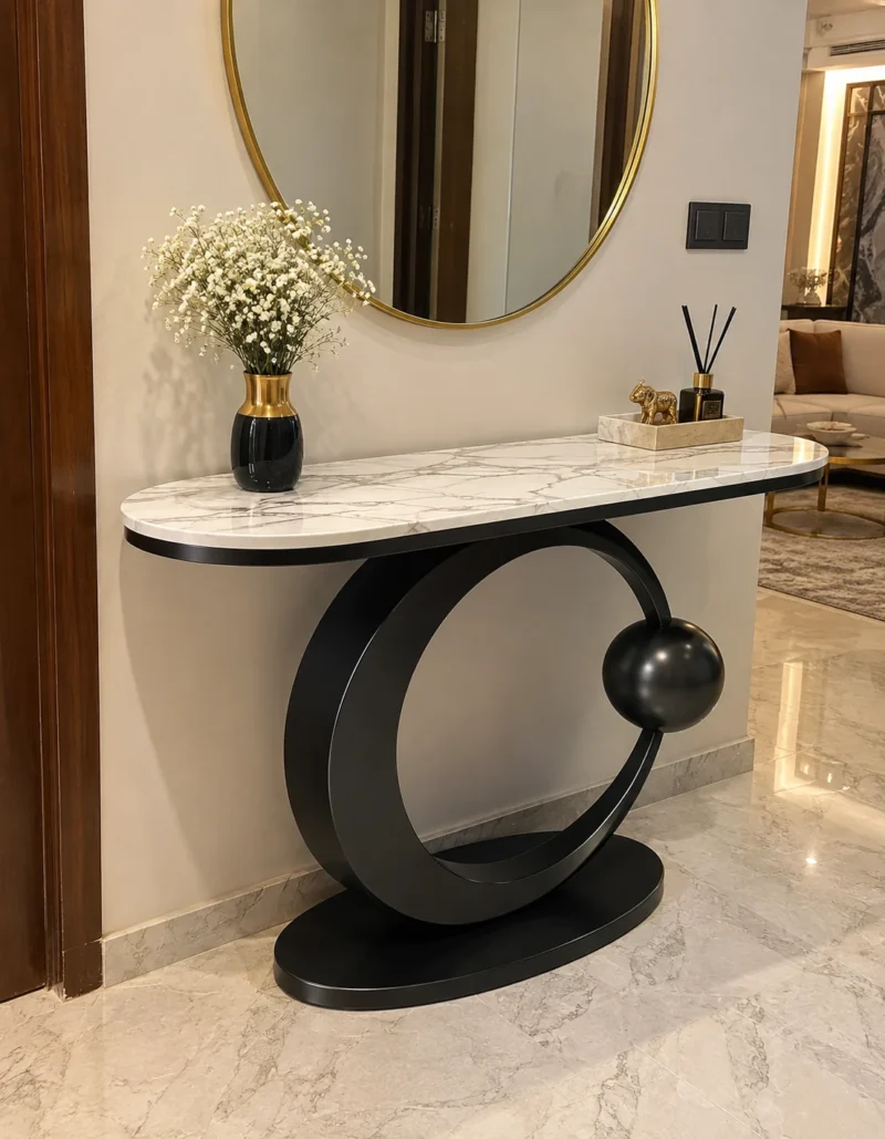 Modern black stainless steel console table with white marble top and circular base in a luxury hallway.