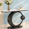 Orbis luxury console table with oval white marble top, black ring pedestal and decorative flower vase.
