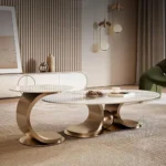 Side view of oval marble nesting table set with champagne gold metal frame on textured beige carpet