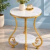 Luxury gold marble side table with curved scrollwork frame styled with flowers against a light blue wall
