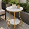 Gold marble side table with decorative curved legs and double-tier shelves displayed beside patio seating