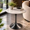 Black Graphite marble side table with round white top beside a cream accent chair in a modern reading corner