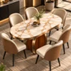 Elevated view of an oval white marble dining table with gold and grey veining, curved pedestal base and upholstered dining chairs.