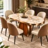 Modern oval marble dining table set with sculptural wood-look and gold pedestal, surrounded by cream and caramel chairs.