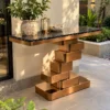 Black marble console table with copper-tone geometric stainless steel base styled with a planter and lantern in a garden-facing terrace.