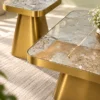 Close-up of grey beige marble coffee table tops with gold veining, rounded corners and brushed gold stainless steel bases.