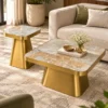 Designer rectangular marble centre table set with gold pedestal bases placed beside a cream sofa in a modern living room.